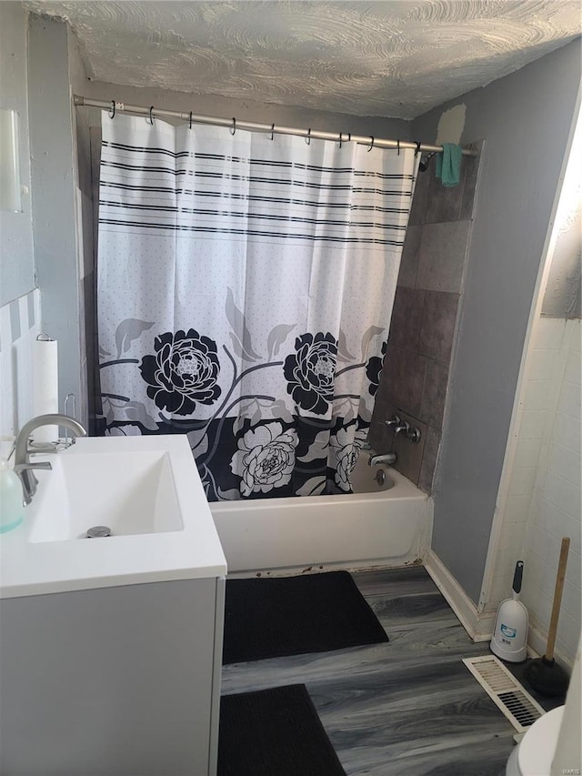 bathroom with vanity, a textured ceiling, hardwood / wood-style flooring, and shower / bath combo with shower curtain