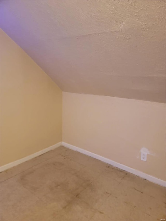 additional living space featuring lofted ceiling and a textured ceiling