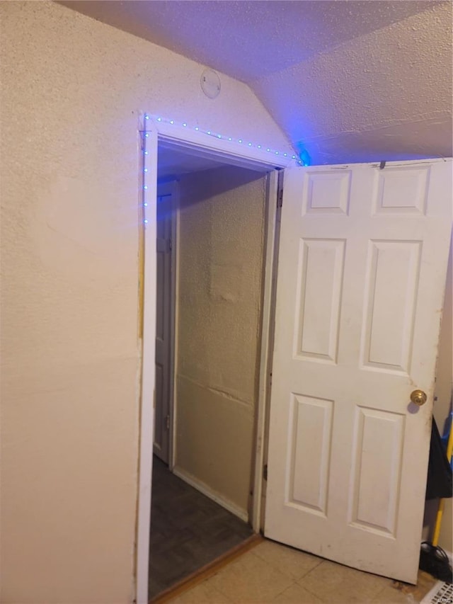 hallway with light tile patterned floors and lofted ceiling