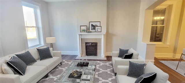 living room with a tiled fireplace and hardwood / wood-style flooring