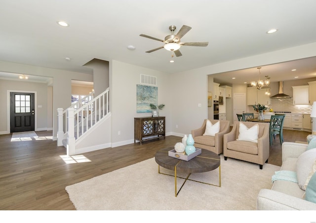 living room with ceiling fan with notable chandelier and hardwood / wood-style floors