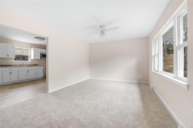 carpeted spare room with ceiling fan and sink