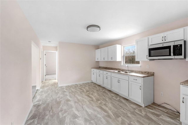 kitchen with sink, white cabinets, and light wood-type flooring