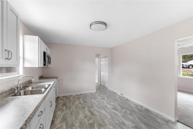 kitchen with white cabinets, stove, light hardwood / wood-style flooring, and sink