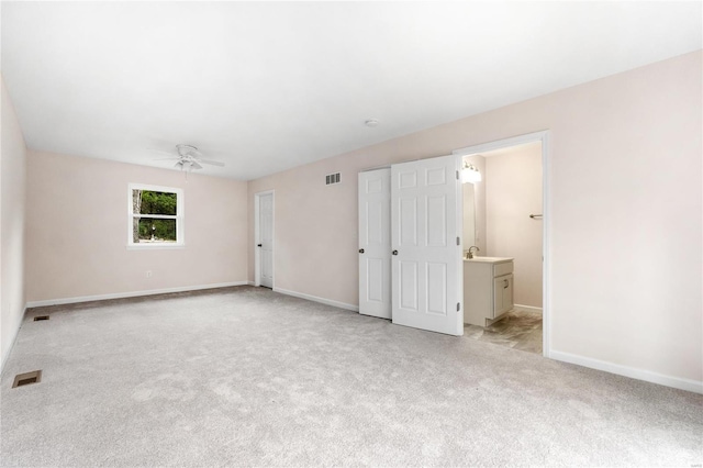 interior space featuring connected bathroom, light carpet, and ceiling fan