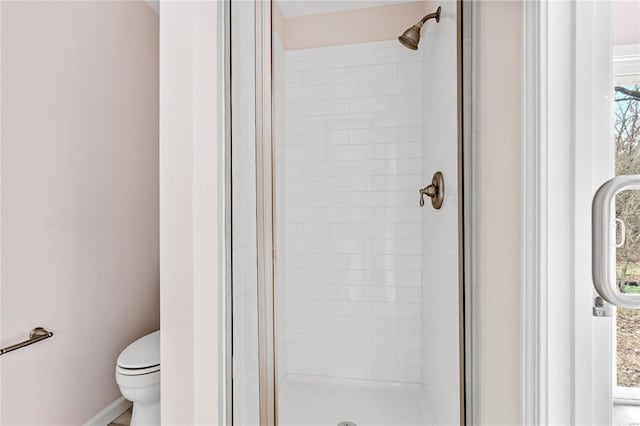 bathroom featuring toilet and a shower with shower door