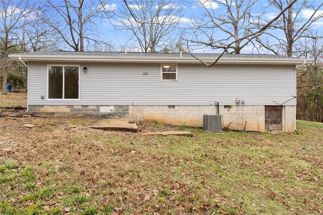 rear view of house with central AC and a lawn