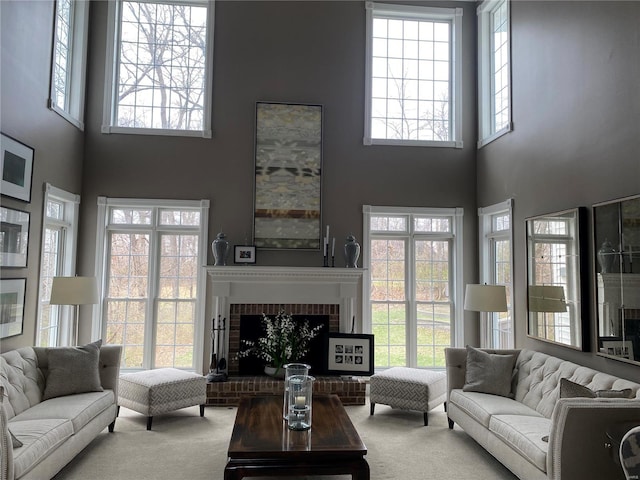 carpeted living room featuring a towering ceiling and a brick fireplace