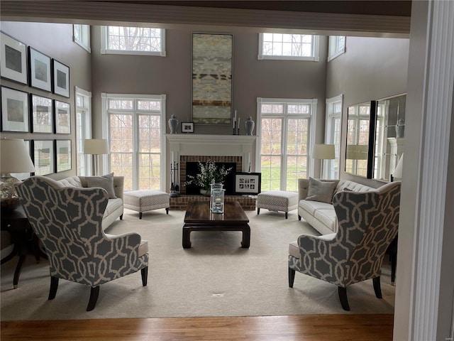 living room featuring light wood-type flooring, a towering ceiling, and a fireplace