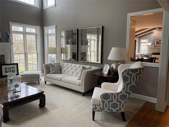 carpeted living room with a notable chandelier, lofted ceiling with beams, and a fireplace