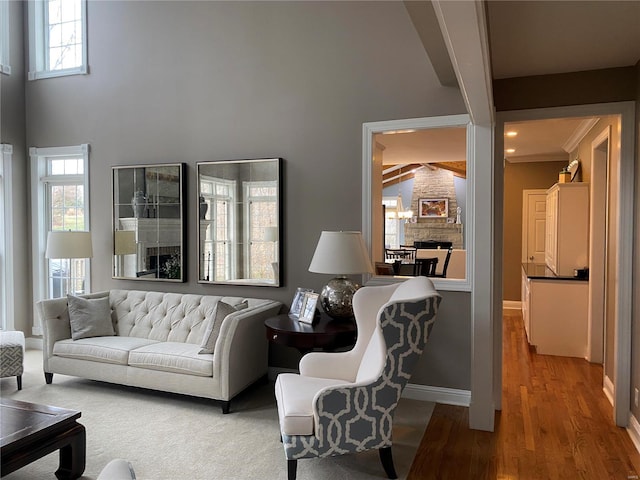 living room with beam ceiling, light hardwood / wood-style flooring, a towering ceiling, and an inviting chandelier