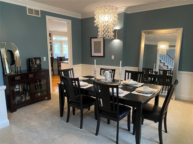 carpeted dining space with ornamental molding and a notable chandelier