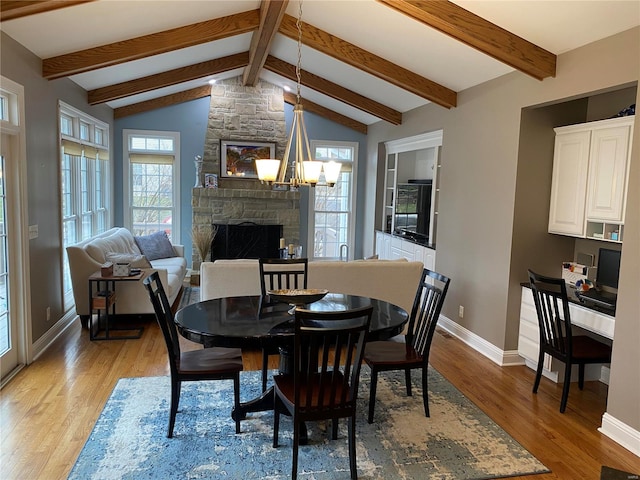 dining space featuring a wealth of natural light, a notable chandelier, light wood-type flooring, and lofted ceiling with beams