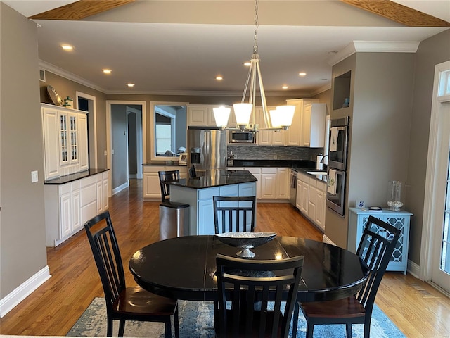 dining space with crown molding, a notable chandelier, light wood-type flooring, and sink