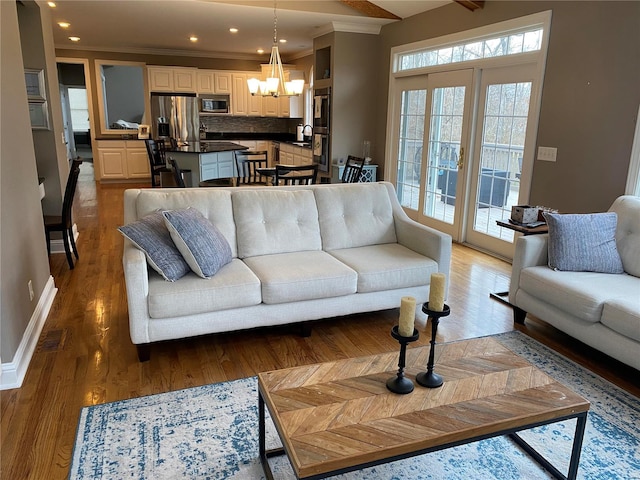 living room featuring ornamental molding, a notable chandelier, sink, and wood-type flooring