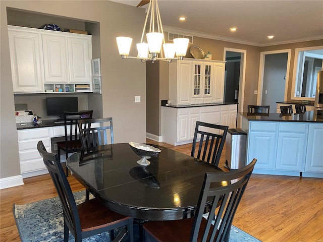 dining room with an inviting chandelier, crown molding, and light hardwood / wood-style floors