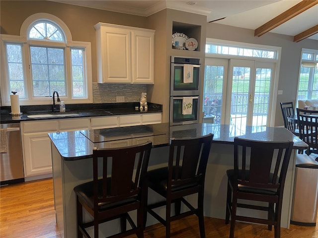 kitchen with light hardwood / wood-style floors, a breakfast bar area, white cabinetry, appliances with stainless steel finishes, and sink