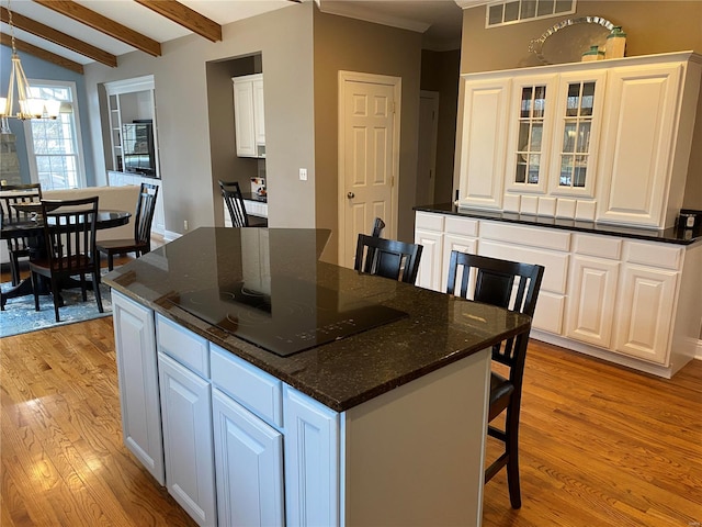 kitchen featuring an inviting chandelier, a breakfast bar area, white cabinetry, light wood-type flooring, and a center island