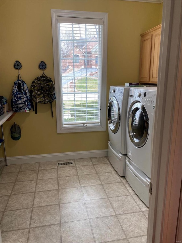 laundry room with washing machine and dryer, a wealth of natural light, cabinets, and light tile floors