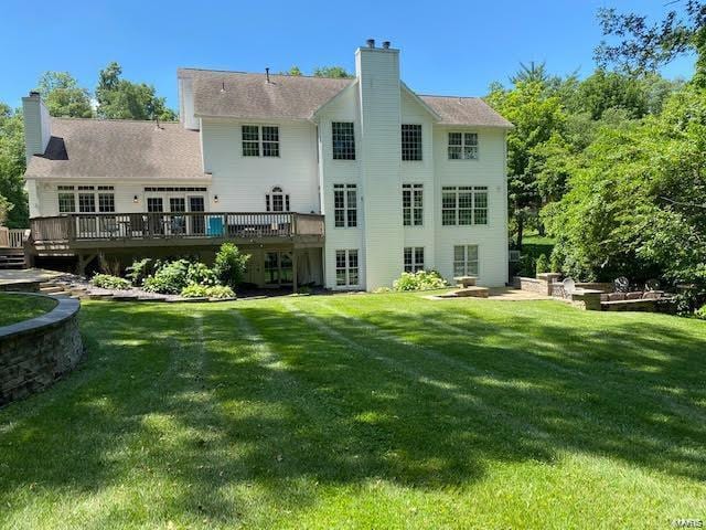 back of property featuring a wooden deck and a yard