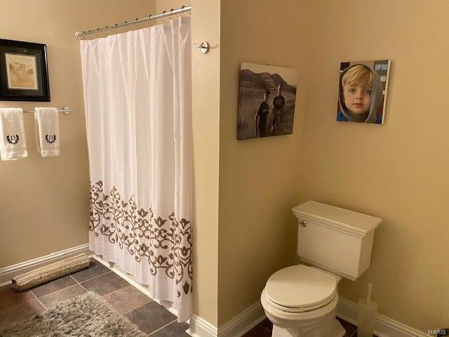 bathroom featuring tile flooring and toilet