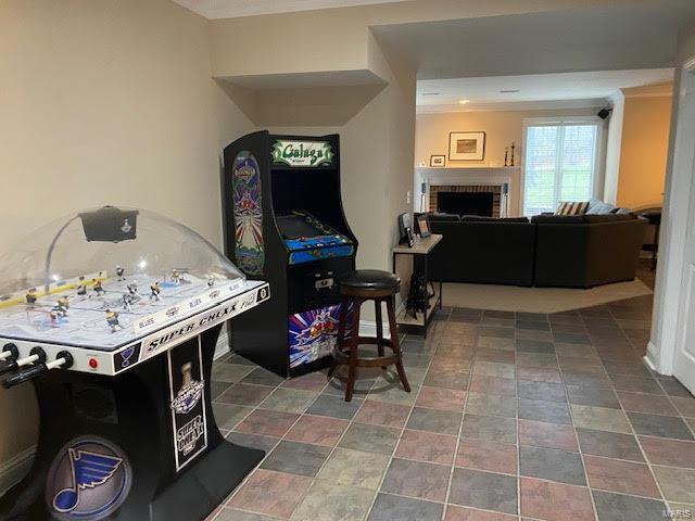 rec room featuring dark tile floors and a brick fireplace