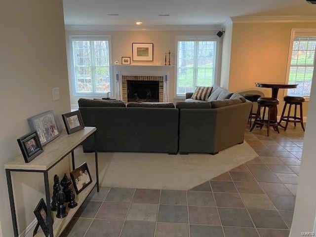 tiled living room with a brick fireplace and crown molding