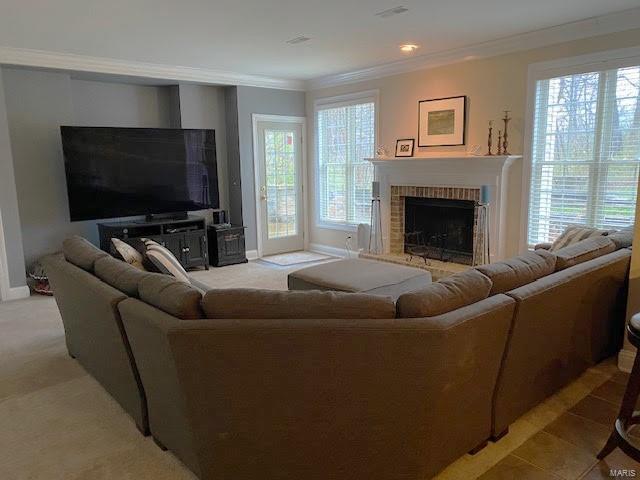 living room featuring ornamental molding and a brick fireplace