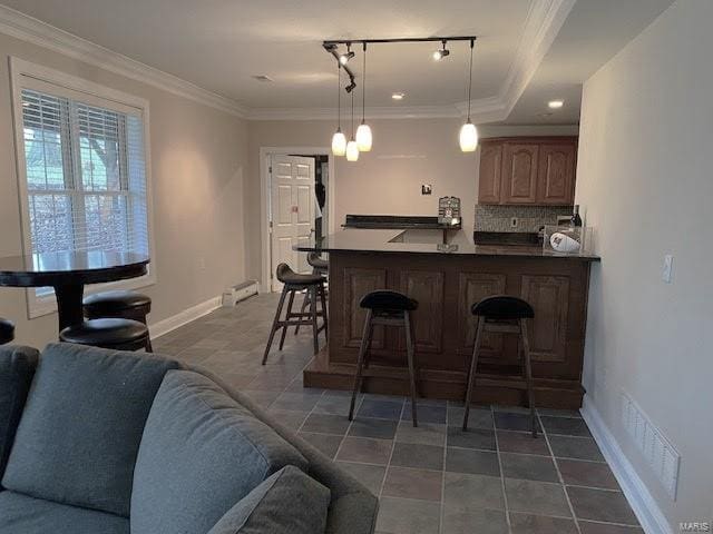 kitchen with a tray ceiling, crown molding, decorative light fixtures, and a breakfast bar