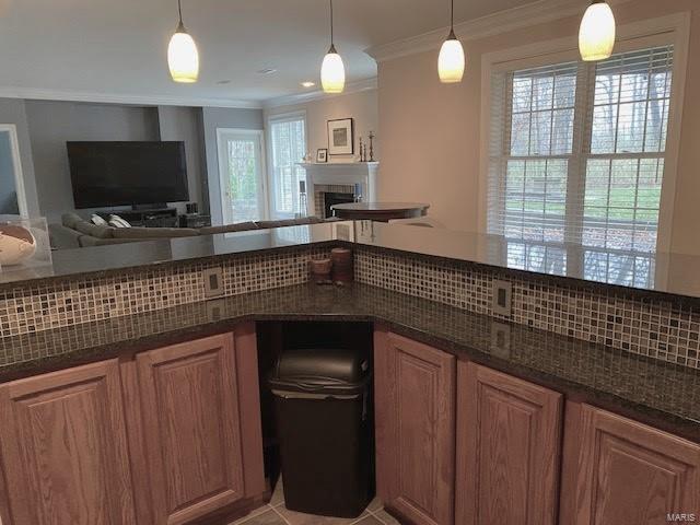 kitchen with dark stone countertops, tasteful backsplash, a wealth of natural light, and pendant lighting