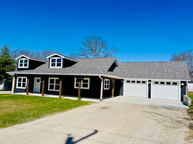 view of front of property with a porch, a front yard, and a garage