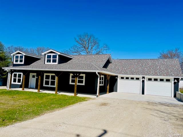 view of front of home with a front lawn, covered porch, and a garage