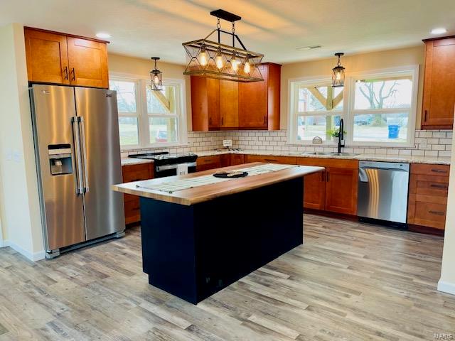 kitchen with a kitchen island, light hardwood / wood-style floors, tasteful backsplash, and stainless steel appliances