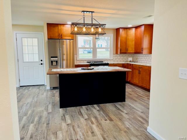 kitchen featuring a kitchen island, tasteful backsplash, hanging light fixtures, and light hardwood / wood-style flooring