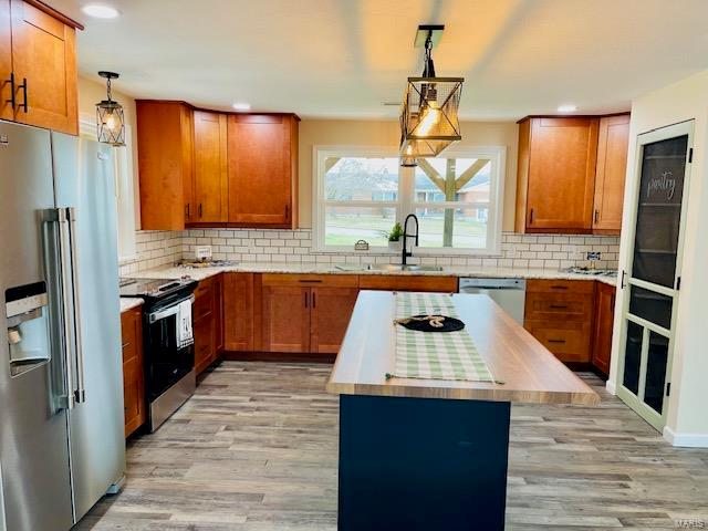 kitchen with backsplash, sink, appliances with stainless steel finishes, and light wood-type flooring