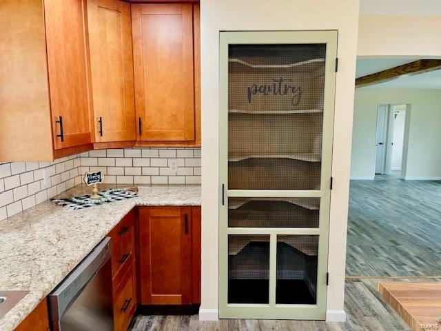 kitchen with backsplash, light stone countertops, dishwasher, and light wood-type flooring