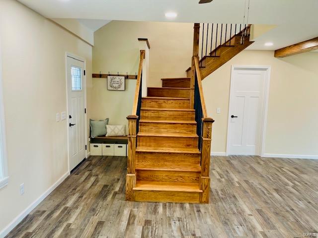 stairway with wood-type flooring and beam ceiling