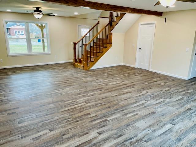 unfurnished living room featuring ceiling fan and dark wood-type flooring