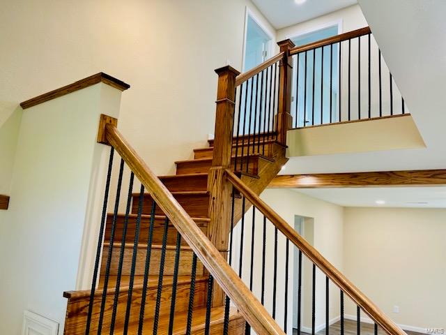 stairs with dark wood-type flooring and a high ceiling