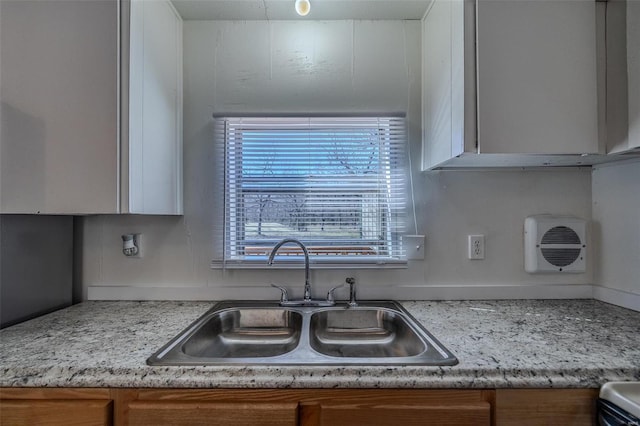 kitchen with white cabinets, sink, and light stone countertops