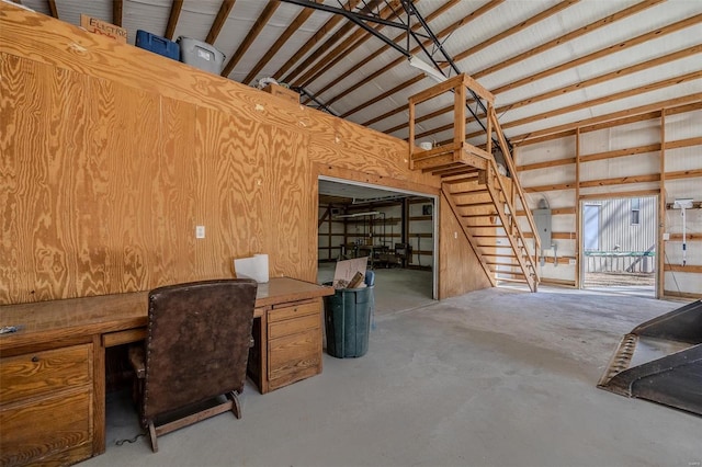 unfurnished office featuring concrete floors, wooden walls, and lofted ceiling