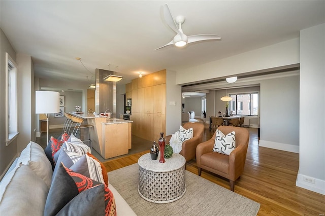 living room with wood finished floors, a ceiling fan, and baseboards