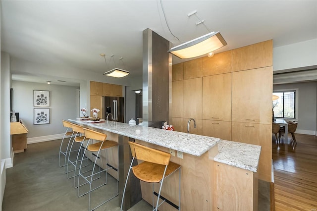 kitchen featuring light stone countertops, modern cabinets, a breakfast bar area, and high end refrigerator