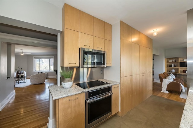 kitchen with appliances with stainless steel finishes, light brown cabinetry, open floor plan, and light stone countertops