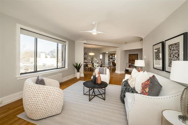 living area featuring light wood-style floors, ceiling fan, and baseboards