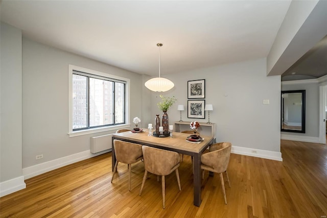 dining room with baseboards, radiator heating unit, and light wood-style floors