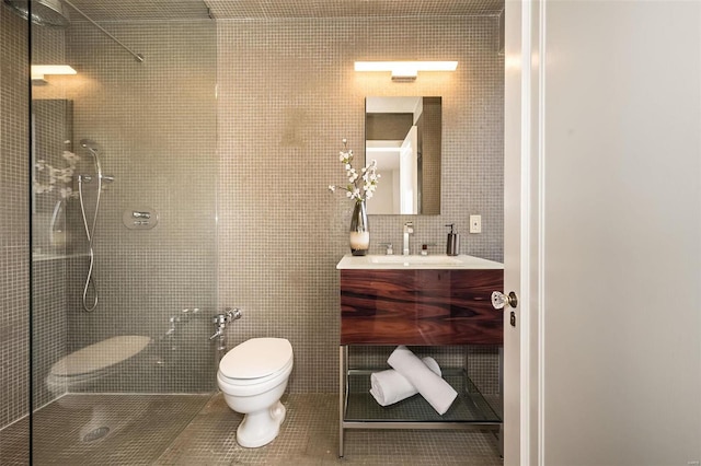 bathroom featuring tile patterned flooring, toilet, vanity, tile walls, and walk in shower