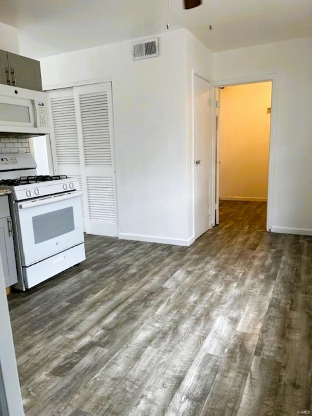 kitchen with decorative backsplash, gray cabinetry, white appliances, dark hardwood / wood-style flooring, and ceiling fan