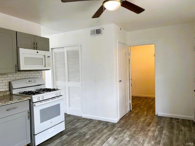 kitchen with backsplash, white appliances, dark hardwood / wood-style flooring, ceiling fan, and stone countertops