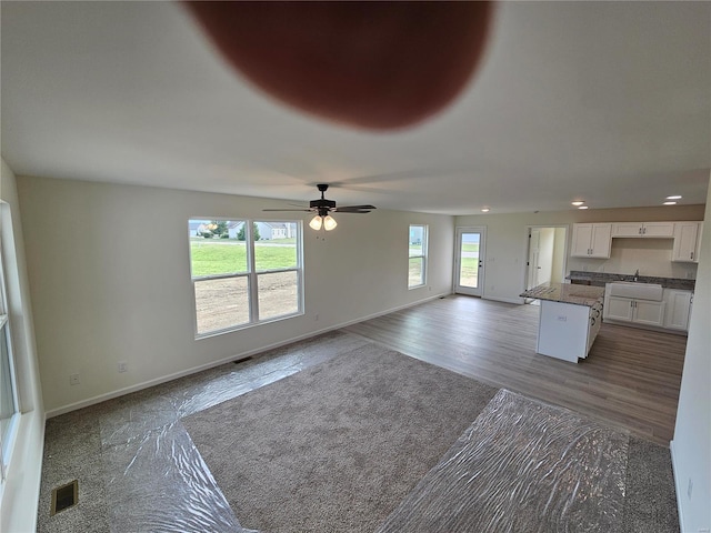 unfurnished living room with ceiling fan and dark wood-type flooring